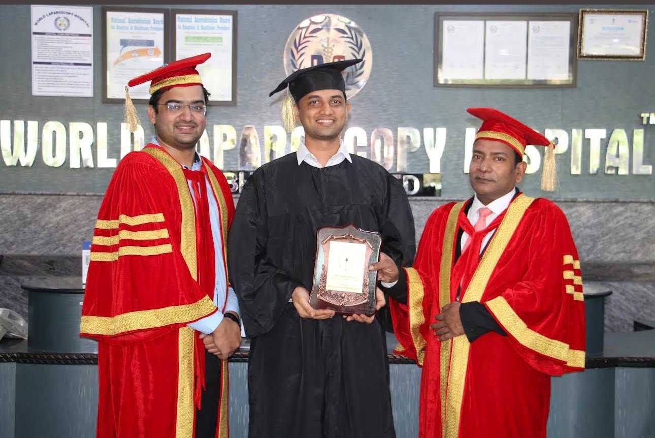 Dr. Kishan Rao in a graduation gown with two colleagues, holding a plaque
